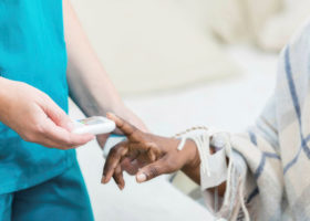 护士使用手持设备测试患者血糖的图像。