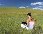 一个年轻的女人在草地上用笔记本电脑