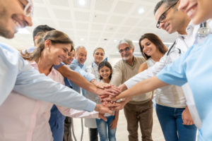 一群医疗保健工作者和不同年龄和种族的患者都在医院微笑着双手。