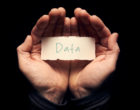 一名男子双手捧着一张卡片，上面手写着“数据”。