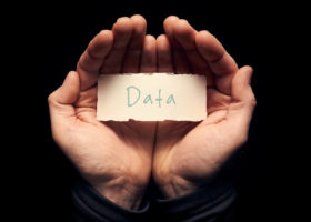 一名男子捧着一张卡片，上面手写着“数据”。